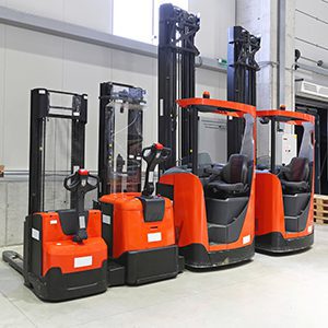 Various trucks lined up in front of wall in corner of warehouse