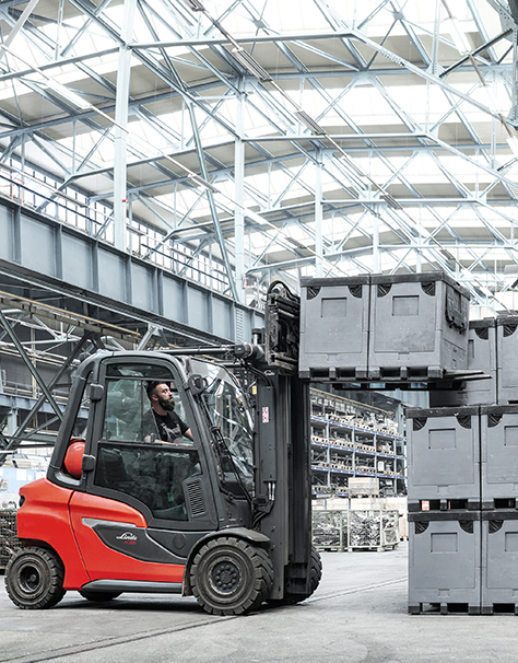 Linde forklift truck lifting grey pallets and stacking them