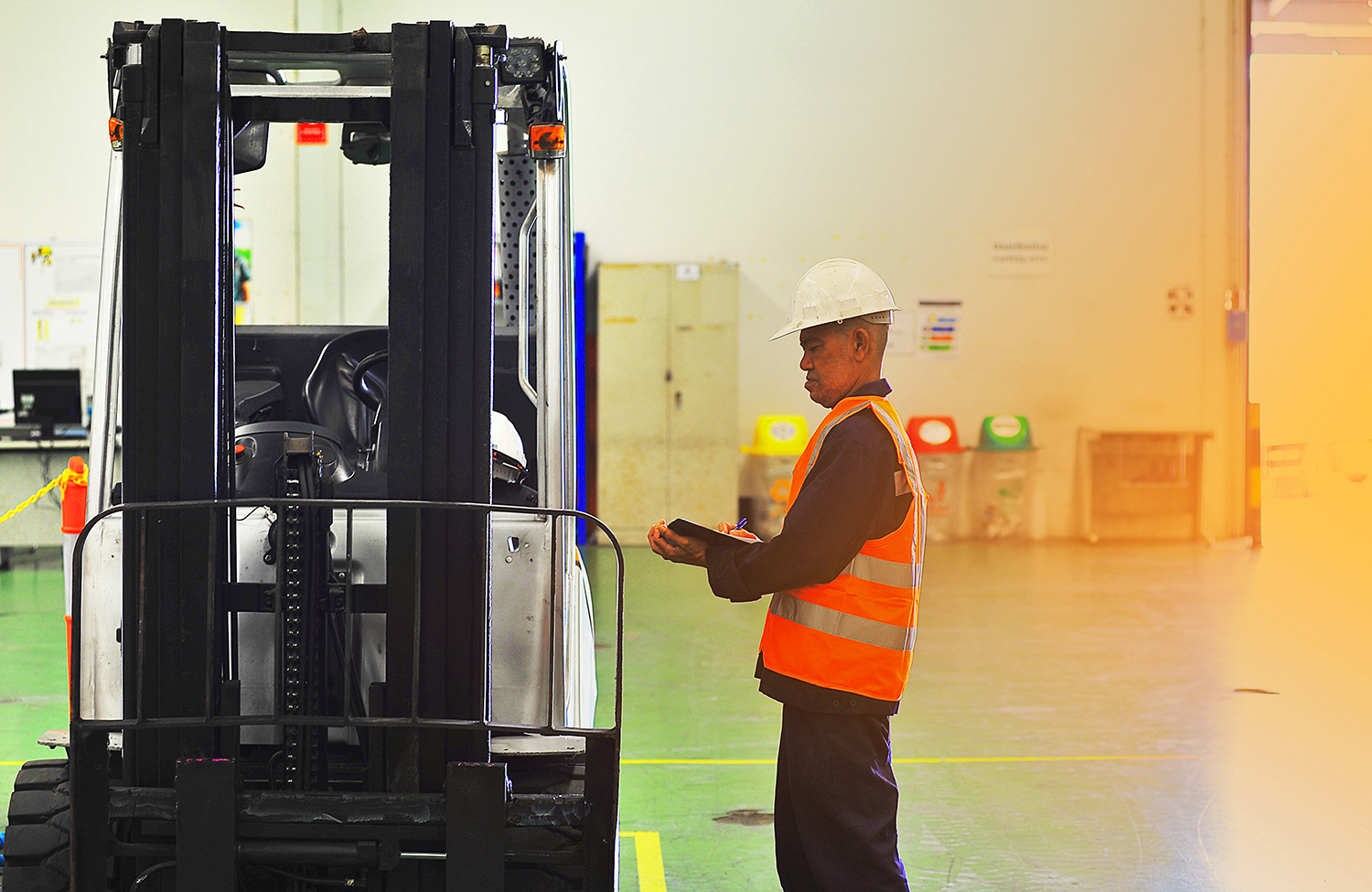 Engineer inspecting a forklift truck holding a clipboard